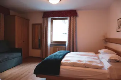 a bedroom with a large bed and a window at Hotel Malga Passerella in Moena