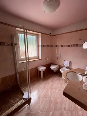 a bathroom with a shower and two sinks and a toilet at Park Hotel Aurora in Pozza di Fassa