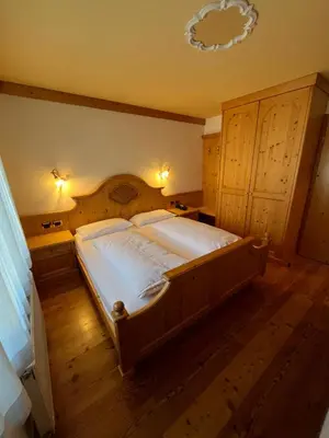 a bedroom with a large bed with a wooden headboard at Park Hotel Aurora in Pozza di Fassa