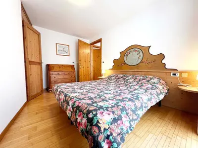 a bedroom with a bed and a wooden floor at Moena Appartamenti in Moena