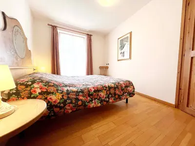 a bedroom with a bed with a floral bedspread at Moena Appartamenti in Moena