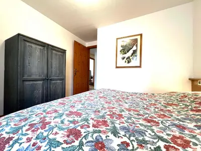 a bedroom with a bed with a floral bedspread at Moena Appartamenti in Moena