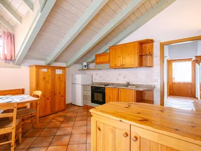 a large kitchen with wooden cabinets and a table at Apartment Cesa Pra da Molin-1 by Interhome in Campitello