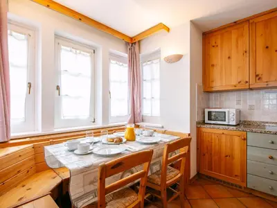 a kitchen with wooden cabinets and a table with chairs at Apartment Cesa Pra da Molin-2 by Interhome in Campitello