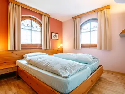 a bedroom with a wooden bed in a room with windows at Apartment Cesa Pra da Molin-3 by Interhome in Campitello