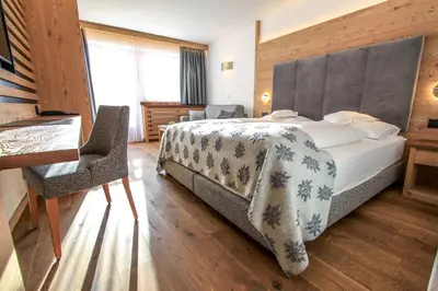 a bedroom with a large bed and a desk at Dolasilla Mountain Panoramic Wellness Hotel in La Villa