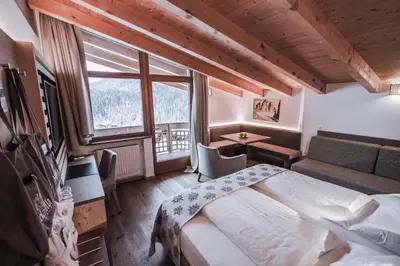 a bedroom with a bed and a large window at Dolasilla Mountain Panoramic Wellness Hotel in La Villa