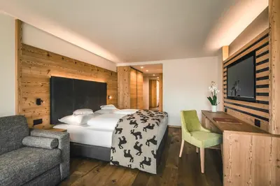 a hotel room with a bed and a couch at Dolasilla Mountain Panoramic Wellness Hotel in La Villa