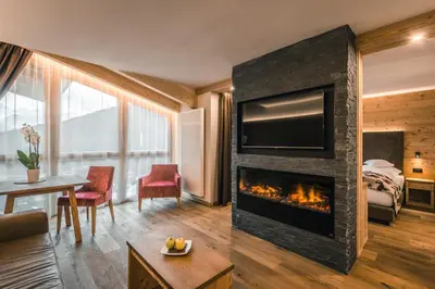 a living room with a fireplace with a television at Dolasilla Mountain Panoramic Wellness Hotel in La Villa