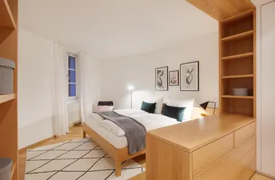 a bedroom with a bed and a wooden desk at Franciscus Apartments in Bolzano