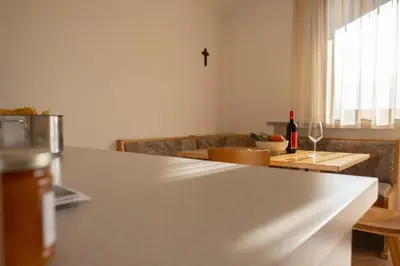 a kitchen with a counter and a table with a wine glass at Fewo Zweiraum im Haus Götsch 5 in Parcines