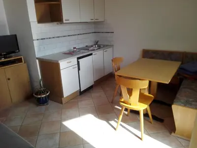 a small kitchen with a wooden table and chairs at Fewo Zweiraum im Haus Götsch 5 in Parcines