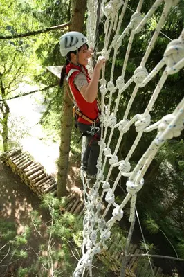 a woman is climbing on a zip line in the forest at Fewo Zweiraum im Haus Götsch 4 in Parcines