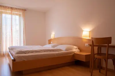 a bedroom with a bed and a chair and a window at Fewo Zweiraum im Haus Götsch 4 in Parcines