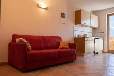 a red couch in a living room with a kitchen at Fewo Zweiraum im Haus Götsch 4 in Parcines