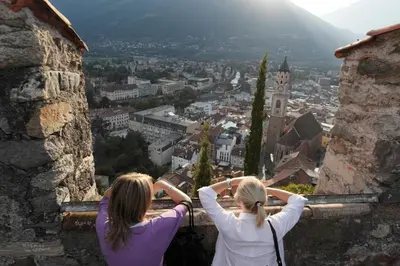 two women sitting on a ledge looking at a city at Fewo Dreiraum im Haus Götsch 3 in Parcines