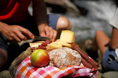 a person cutting cheese and fruit on a cutting board at Fewo Dreiraum im Haus Götsch 3 in Parcines