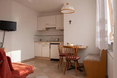 a small kitchen with a table and a cross on the wall at Fewo Zweiraum im Haus Götsch 1 in Parcines