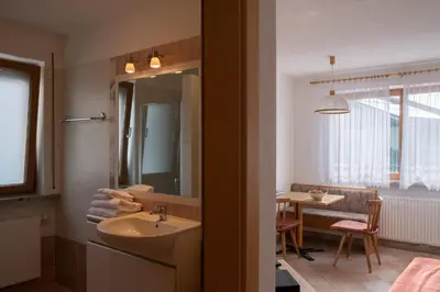 a bathroom with a sink and a mirror and a table at Fewo Zweiraum im Haus Götsch 1 in Parcines
