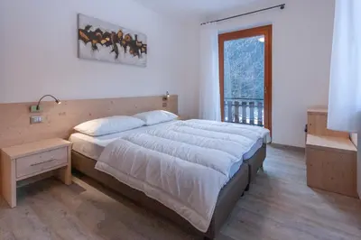 a bedroom with a large bed and a window at Casa Zulian in Falcade