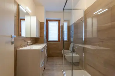 a bathroom with two sinks and a toilet and a shower at Casa Zulian in Falcade