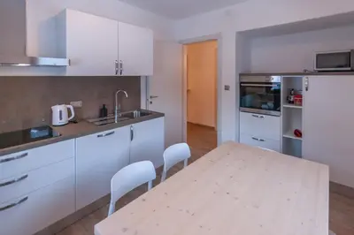 a kitchen with a wooden table and white cabinets at Casa Zulian in Falcade