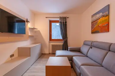 a living room with a couch and a tv at Casa Zulian in Falcade