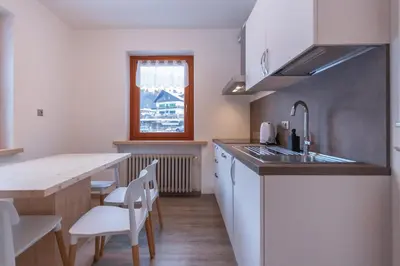 a kitchen with a sink and a table with chairs at Casa Zulian in Falcade