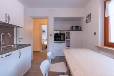 a kitchen with a wooden table and white cabinets at Casa Zulian in Falcade