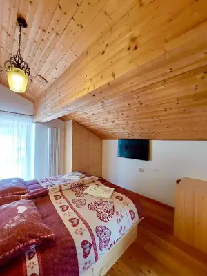 a large bed in a room with a wooden ceiling at Rifugio Palafavera in Val di Zoldo