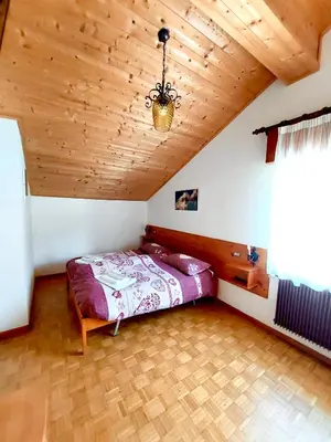 a bedroom with a bed and a wooden ceiling at Rifugio Palafavera in Val di Zoldo