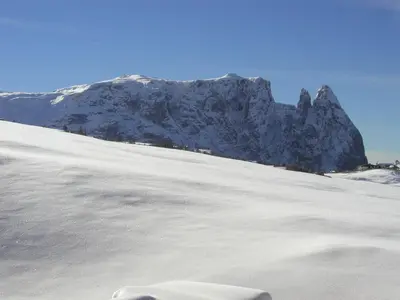 a snow covered mountain in front of a snow covered slope at Appartements Karbon in Seiser Alm