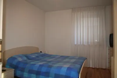 a bedroom with a blue plaid blanket on a bed at Appartamenti Piazzi in Tesero