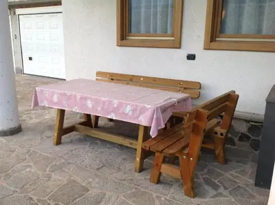 a table and a bench with a pink table cloth at Appartamenti Piazzi in Tesero