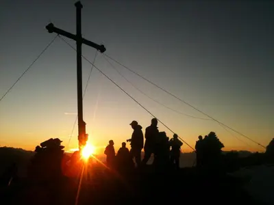 a group of people standing around a cross at sunset at Hotel Ratschingserhof in Racines