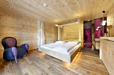 a bedroom with a large bed and a chair at Hotel Ratschingserhof in Racines