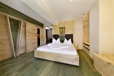 a bedroom with a white bed and wooden walls at Hotel Ratschingserhof in Racines