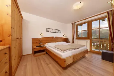 a bedroom with a wooden bed and a large window at Nestlhof in Racines