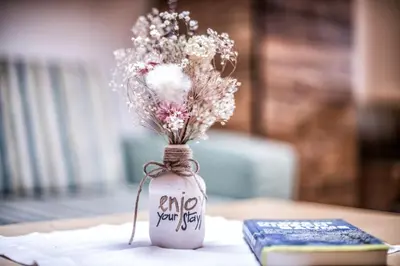 a vase with flowers in it next to a book at Nestlhof in Racines