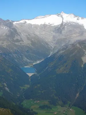 a mountain valley with a lake and snow covered mountains at Cafe Schneider in Lappago