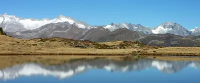 a mountain range with a reflection in a body of water at Cafe Schneider in Lappago