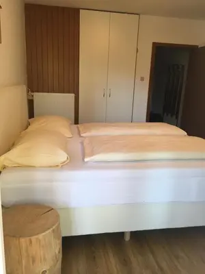 a large white bed in a room with a wooden floor at Burgfrieden in Vipiteno