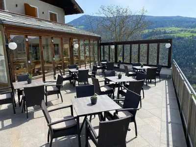 a restaurant with tables and chairs on a balcony at Sturmhof in Chiusa