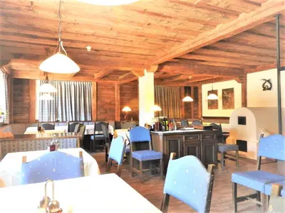 a restaurant with wooden ceilings and blue chairs and tables at Residence Tantalus in San Lorenzo di Sebato