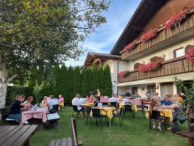a group of people sitting at tables in front of a building at Pension Volgger in Rodengo