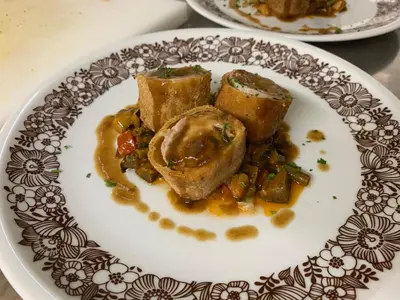 a plate of food with meat and vegetables on a table at Pension Volgger in Rodengo