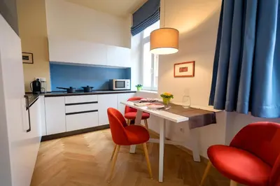 a small kitchen with a table and red chairs at App110 in Merano