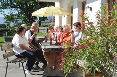 a group of people sitting at a table under an umbrella at Der Brunnerhof in Mühlbach
