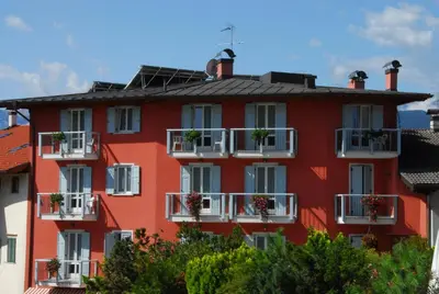 a red building with flowerpots on the balconies at Hotel Sport in Coredo