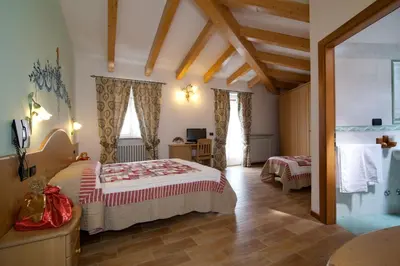 a bedroom with a large bed and two windows at Hotel Sport in Coredo